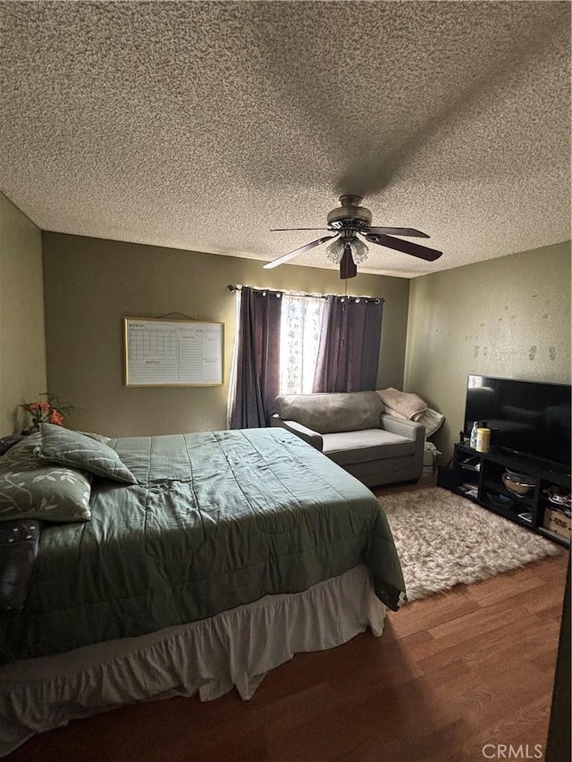 bedroom featuring ceiling fan, wood-type flooring, and a textured ceiling