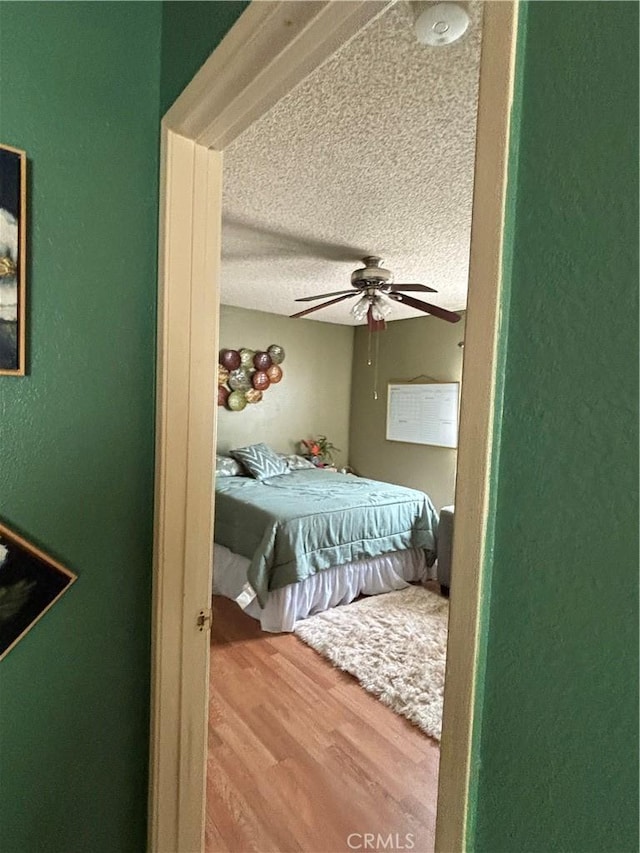 bedroom featuring wood-type flooring, a textured ceiling, and ceiling fan