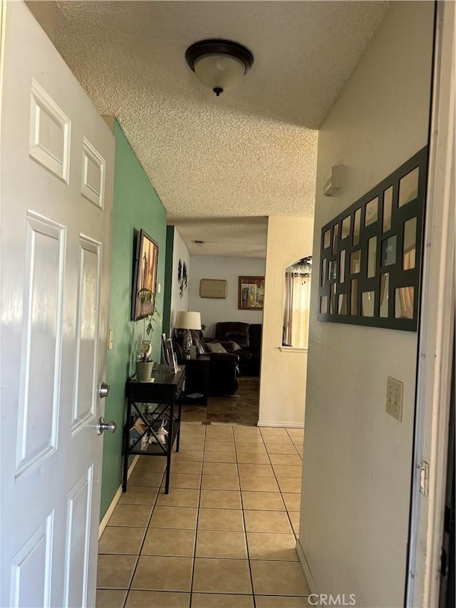 hallway featuring light tile patterned floors and a textured ceiling