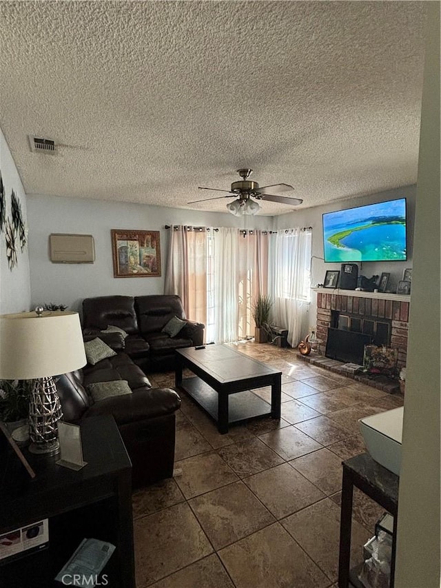 tiled living room with ceiling fan, a textured ceiling, and a brick fireplace