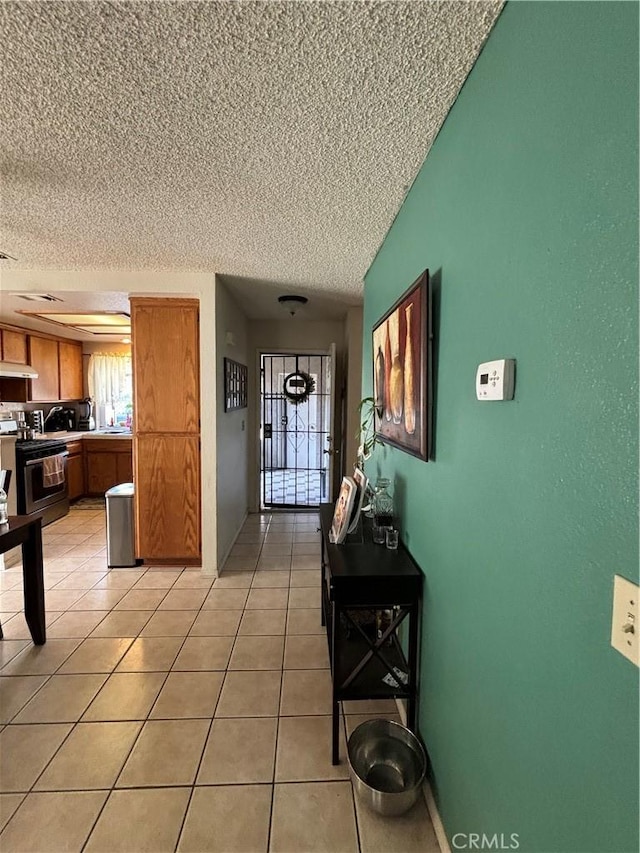 hallway with a textured ceiling and light tile patterned flooring