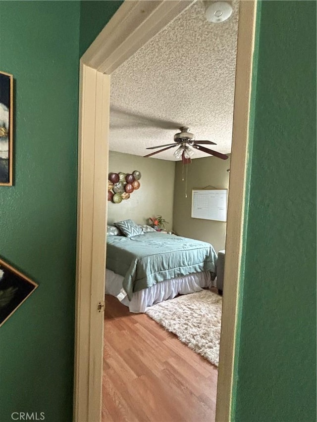 bedroom featuring ceiling fan, a textured ceiling, and hardwood / wood-style flooring