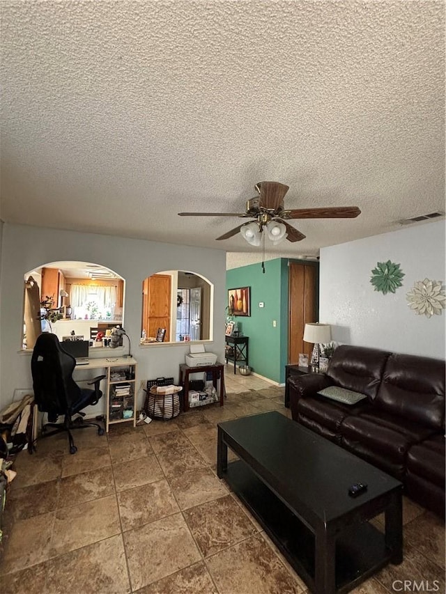 living room with a textured ceiling and ceiling fan