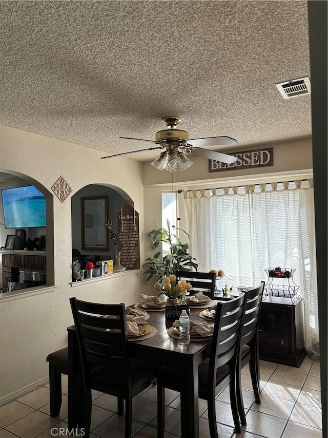 tiled dining space featuring ceiling fan and a textured ceiling