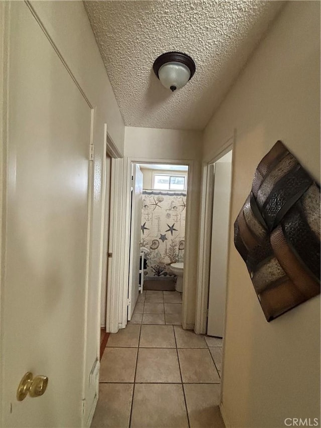 corridor featuring light tile patterned floors and a textured ceiling