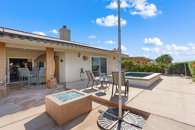 view of patio / terrace with an in ground hot tub and a fire pit