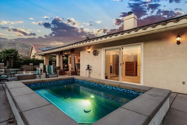 pool at dusk with a patio area and a mountain view