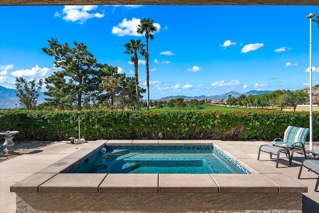 view of pool featuring a patio area, a mountain view, and an in ground hot tub