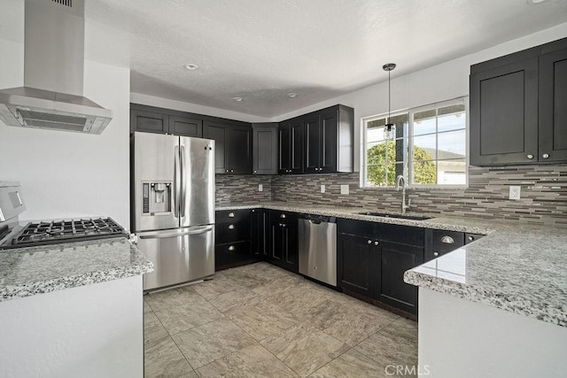 kitchen with light stone countertops, stainless steel appliances, sink, wall chimney range hood, and hanging light fixtures