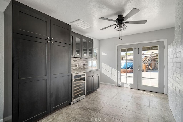 kitchen with light stone countertops, french doors, a textured ceiling, beverage cooler, and ceiling fan