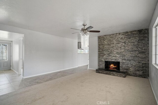 unfurnished living room featuring a textured ceiling, a fireplace, ceiling fan, and light carpet