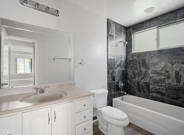 full bathroom with vanity, a textured ceiling, hardwood / wood-style floors, toilet, and tiled shower / bath