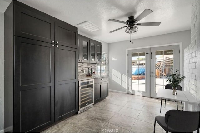 bar featuring backsplash, french doors, ceiling fan, a textured ceiling, and beverage cooler