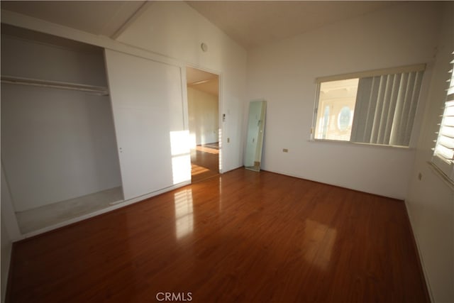 unfurnished bedroom featuring lofted ceiling, wood-type flooring, and a closet