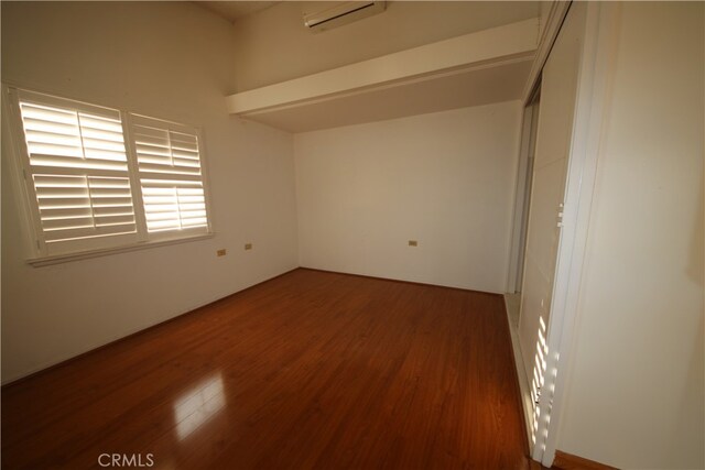 spare room featuring a wall mounted AC and dark hardwood / wood-style floors