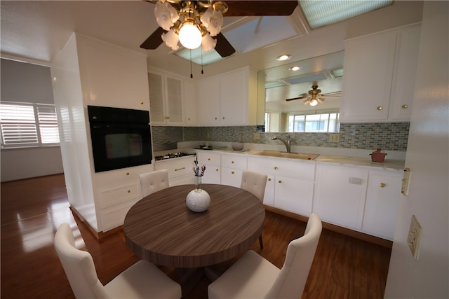 kitchen featuring oven, backsplash, white cabinetry, dark wood-type flooring, and sink