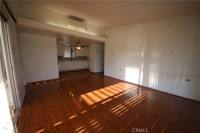 unfurnished room featuring a textured ceiling, a wall mounted AC, dark wood-type flooring, and ceiling fan