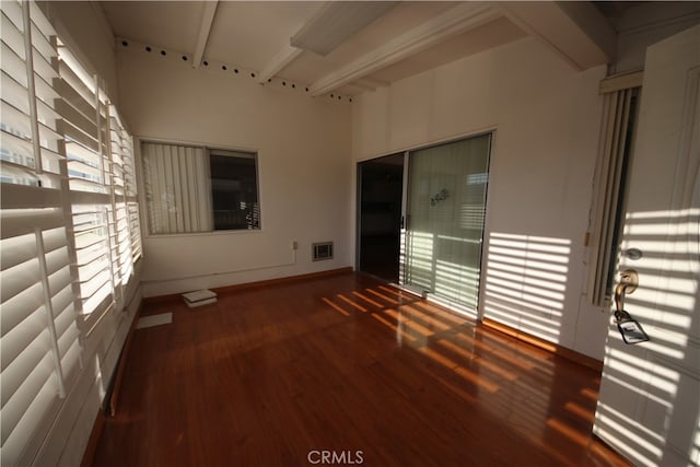 spare room with beam ceiling, plenty of natural light, and dark hardwood / wood-style floors