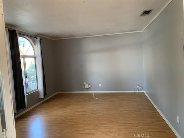 spare room with light wood-type flooring and crown molding