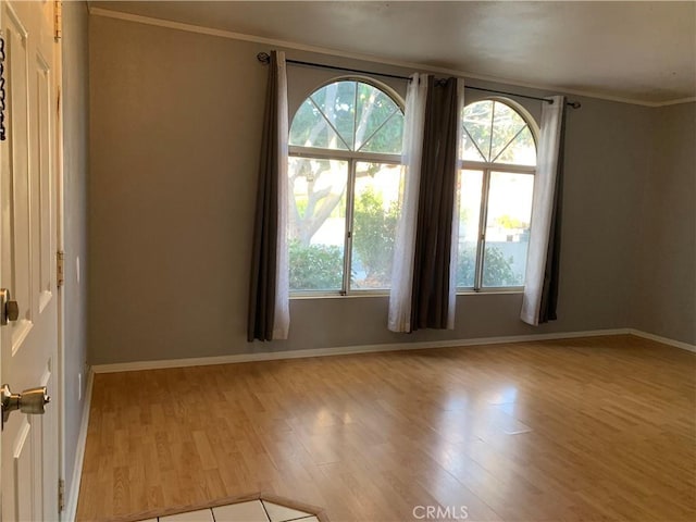 spare room with plenty of natural light, light hardwood / wood-style floors, and ornamental molding