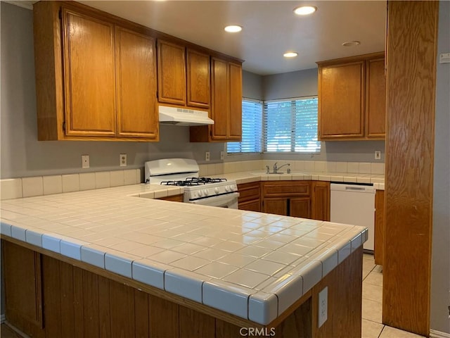 kitchen with kitchen peninsula, light tile patterned floors, white appliances, and tile countertops