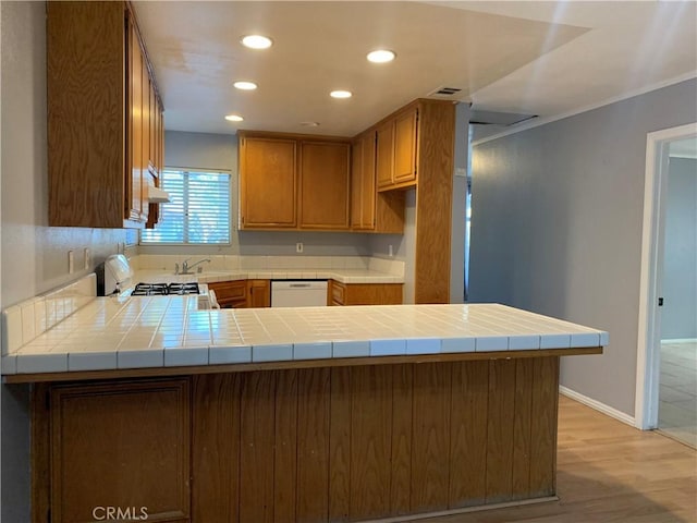 kitchen featuring tile counters, dishwasher, kitchen peninsula, and light wood-type flooring