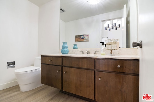 bathroom featuring hardwood / wood-style floors, a notable chandelier, toilet, and vanity