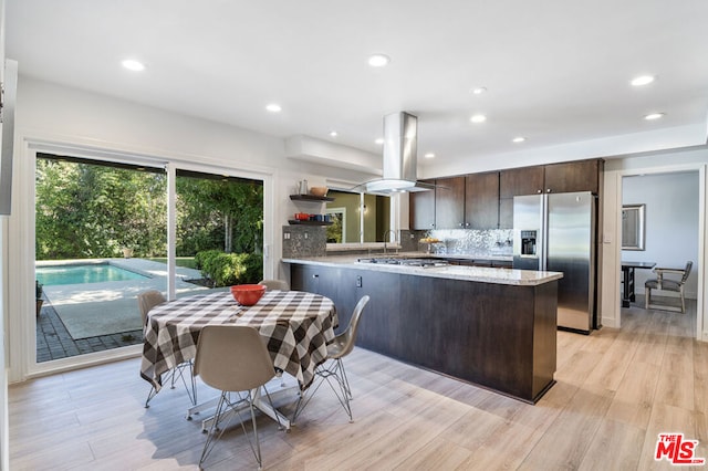 kitchen with light wood-type flooring, dark brown cabinets, kitchen peninsula, island exhaust hood, and stainless steel appliances