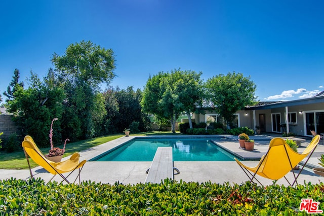 view of swimming pool featuring a diving board