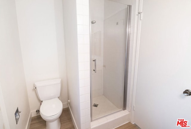 bathroom featuring an enclosed shower, toilet, and wood-type flooring