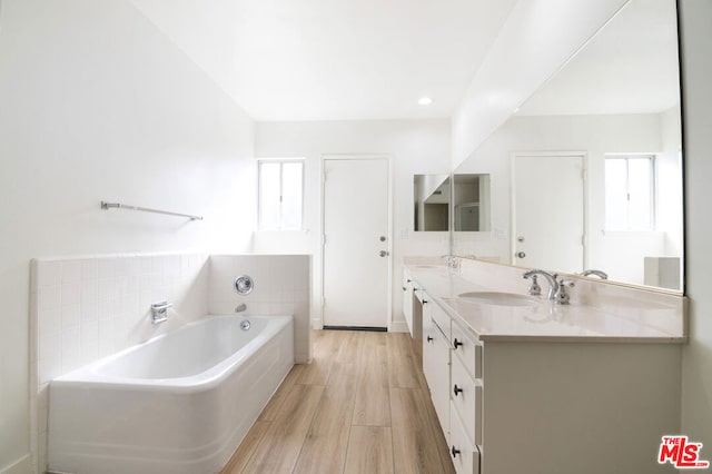 bathroom featuring vanity, a bath, and hardwood / wood-style flooring