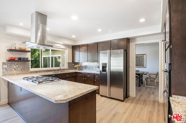 kitchen featuring sink, light wood-type flooring, appliances with stainless steel finishes, island range hood, and kitchen peninsula