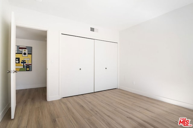 unfurnished bedroom featuring light wood-type flooring and a closet