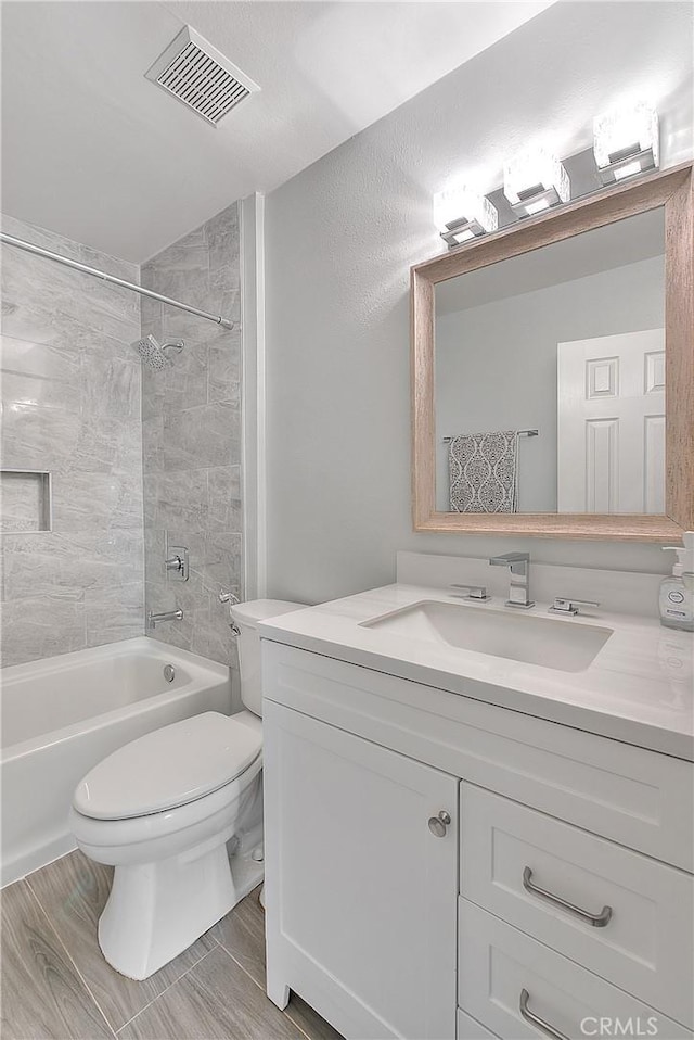 full bathroom with vanity, toilet, tiled shower / bath, and hardwood / wood-style flooring