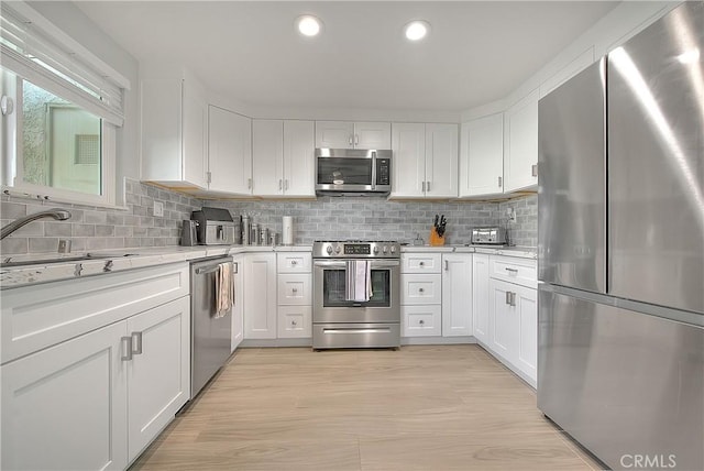 kitchen featuring white cabinets, light hardwood / wood-style floors, and appliances with stainless steel finishes