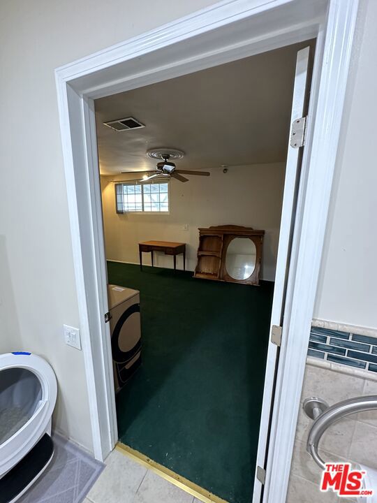 bathroom featuring tile patterned flooring, washer / dryer, and ceiling fan