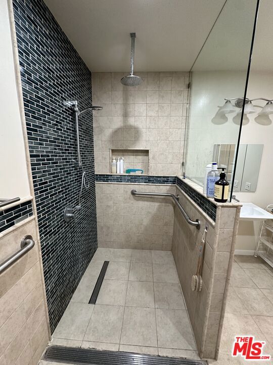 bathroom featuring tiled shower, tile patterned floors, and tile walls