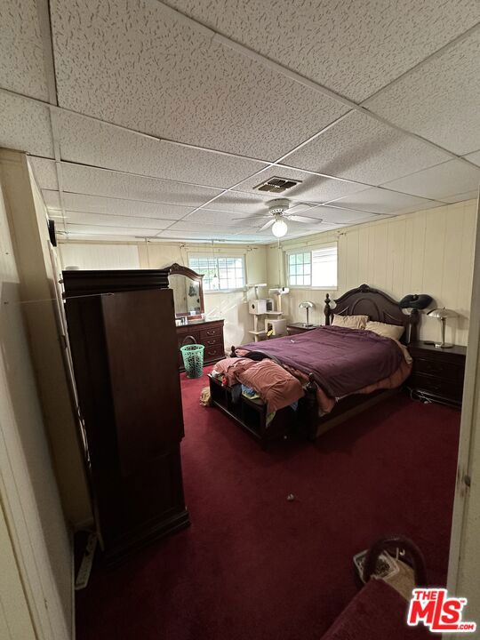 carpeted bedroom with a drop ceiling and ceiling fan