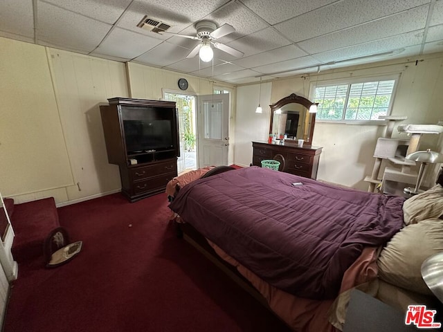 bedroom featuring ceiling fan, dark carpet, and a drop ceiling