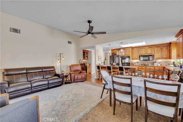 living room with light hardwood / wood-style floors, ceiling fan, and sink