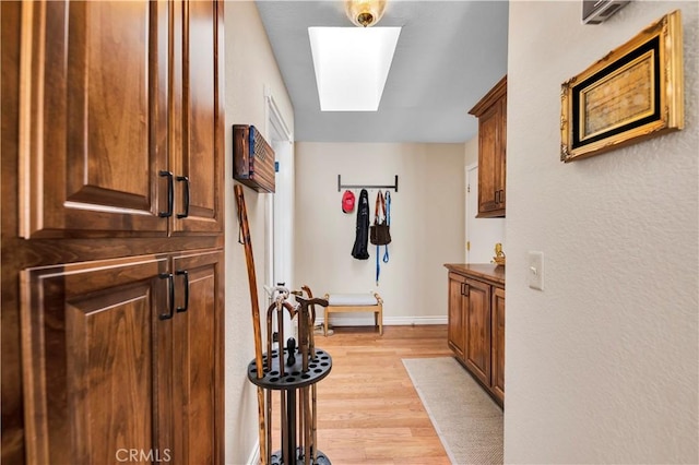 hall with light hardwood / wood-style floors and a skylight