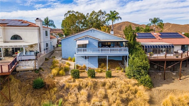 rear view of property with a mountain view and solar panels