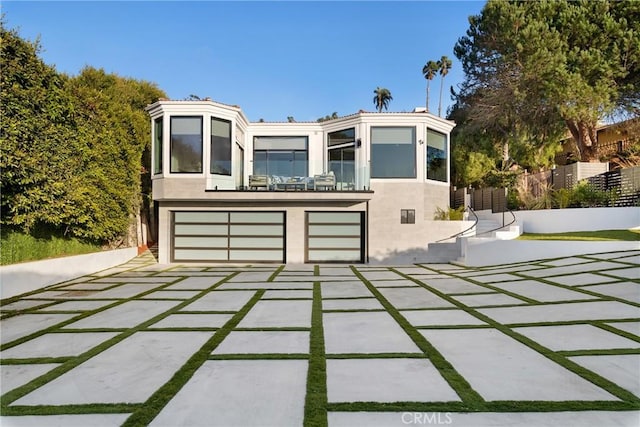 view of front of property featuring an attached garage, fence, and stucco siding