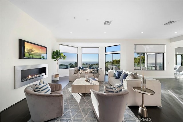 living room featuring a glass covered fireplace, visible vents, and recessed lighting