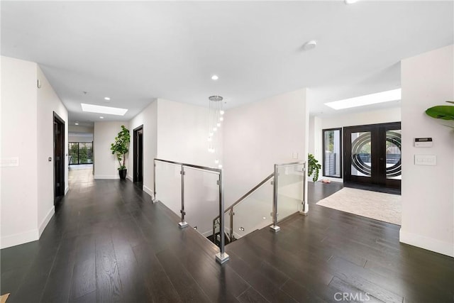 hall featuring recessed lighting, a skylight, wood finished floors, an upstairs landing, and baseboards