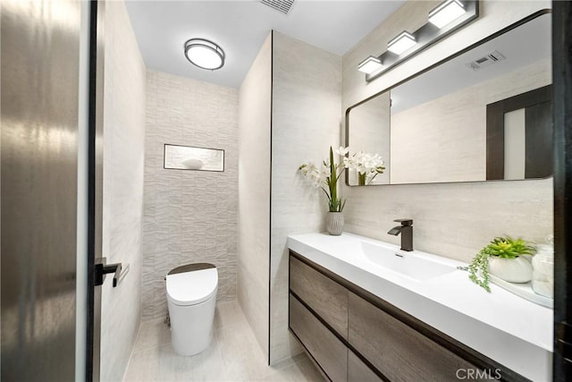 bathroom with tile walls, visible vents, toilet, vanity, and tile patterned floors