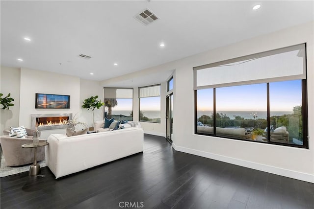 living room with dark wood-style floors, recessed lighting, visible vents, and a lit fireplace