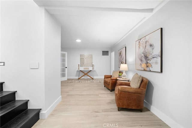 sitting room featuring stairway, light wood-style flooring, visible vents, and baseboards