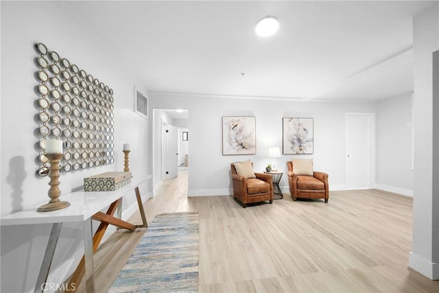 sitting room with baseboards, visible vents, and wood finished floors