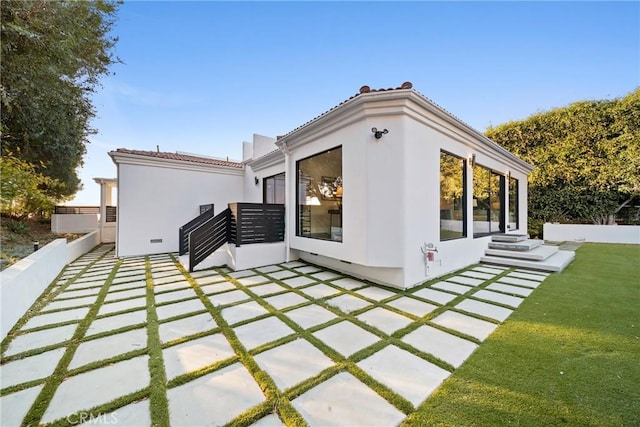 rear view of house with a patio area, a lawn, a tiled roof, and stucco siding